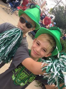 two young boys in green hats with green/white pom poms and Green Top t-shirts celebrating
