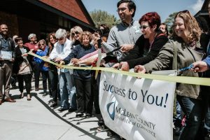 line up of people with scissors at a ribbon cutting in front of the store.