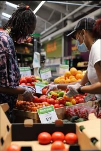 two female staff members stocking produce