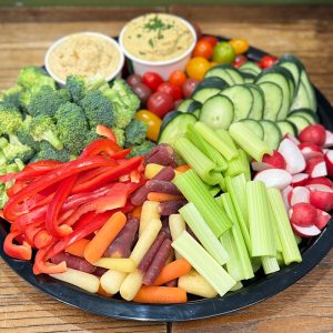 16" tray piled with broccoli florets, sliced red pepper, rainbow baby carrots, celery sticks, red radishes, cucumber slices, cherry tomatoes, and two cups of hummus