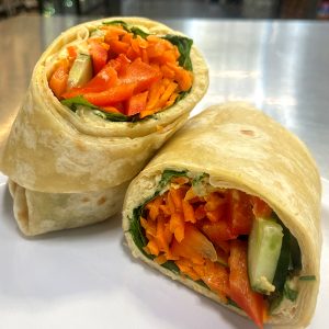 wrap, sliced in half showing shredded carrots, pepper, cucumber and hummus