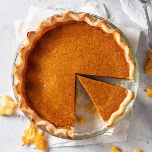 overhead photo of a fresh pumpkin pie with two slices cut, one gone.