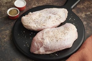 boneless turkey breasts in an iron skillet with herbs and seasonings around