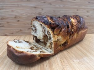 loaf of pumpkin nut babka on a cutting board, with a slice laying in front.